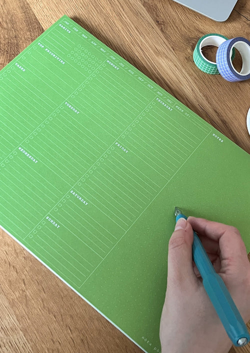 nóta póca A4 weekly desk pad in forest green on desk with pen