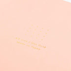 Midori A5 pink dot grid notebook with pen on desk